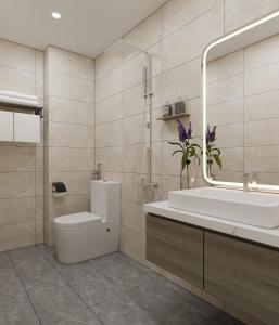 een badkamer met een wastafel, een toilet en een spiegel bij Montcalm Hotel Saigon in Ho Chi Minh-stad