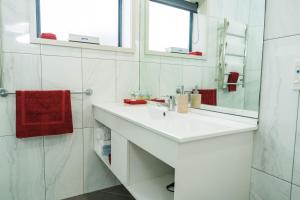 a white bathroom with a sink and a mirror at Aubyn Court Spa Motel in Palmerston North