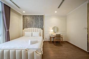 a bedroom with a white bed and a table at Vinhomes Central Park - PHAN DANG Residences in Ho Chi Minh City
