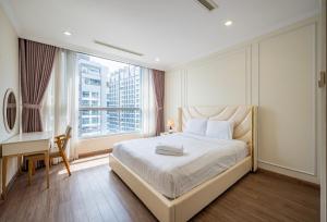 een slaapkamer met een bed, een bureau en een raam bij Vinhomes Central Park - PHAN DANG Residences in Ho Chi Minh-stad