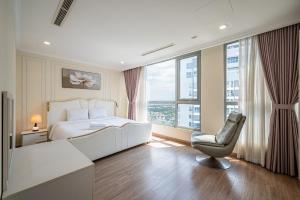 a bedroom with a white bed and a chair and window at Vinhomes Central Park - PHAN DANG Residences in Ho Chi Minh City