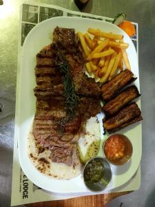 un plato de comida con carne y patatas fritas en Guapote Lodge, en Tigra