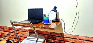 un ordenador portátil sentado en un escritorio con una lámpara en Hotel Cida Flats - Apartamento Charmoso com 300 Mbps, en Boa Vista