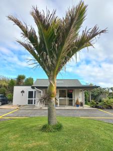 a palm tree in front of a building at Karamea River Motels in Karamea