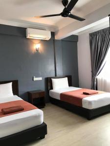 a bedroom with two beds and a ceiling fan at Zaque's Hotel in Sungai Petani