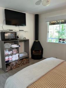 um quarto com uma lareira, uma televisão e uma cama em Chalé Shakti em Teresópolis