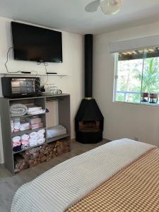 a bedroom with a fireplace with a television and a bed at Chalé Shakti in Teresópolis
