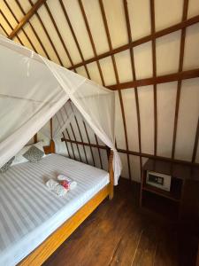 a bed in a room with a wooden floor at We'Be Cottages in Gili Meno