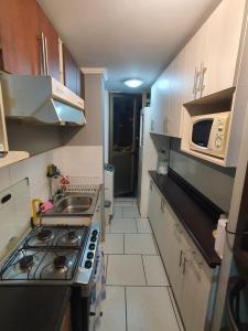 a small kitchen with a stove and a microwave at departamento Arica verano 2 habitaciones in Arica