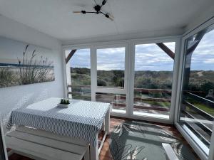 a white room with a table and chairs and windows at Panorama d'EXCEPTION sur Domaine Naturel Protégé et la Mer proche centre La Crête des Dunes Maison complète ou APT uniquement in Le Touquet-Paris-Plage