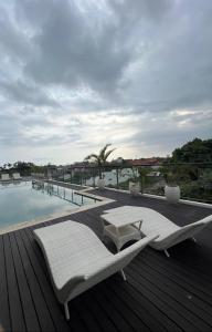 a deck with two lounge chairs and a swimming pool at Penthouse Berawa - Canggu in Canggu
