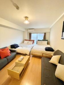 Una sala de estar con dos camas y un sofá en Station Front SHINIMAMIYA 501, en Osaka