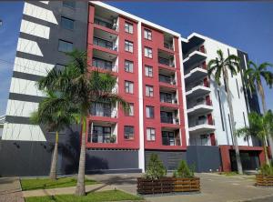 a red building with palm trees in front of it at Beaufort Ridge Apartments Accra in Accra