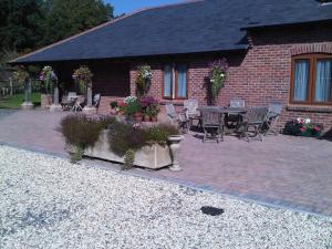 eine Terrasse mit einem Tisch und Stühlen sowie ein Haus in der Unterkunft The Old Dairy Farm in Emsworth