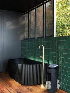 baño con bañera negra y azulejos verdes en 'Sydney' - Luxurious waterfront penthouse in Battery Point, en Hobart
