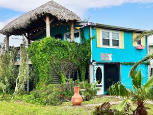 a blue house with a thatch roof at Salty Dog Cottage in Surfside Beach
