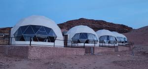 three domes in the desert with a mountain in the background at rum guest house in Wadi Rum