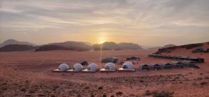 a group of domes in the desert with the sunset at rum guest house in Wadi Rum