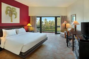 Habitación de hotel con cama, escritorio y TV. en Manado Tateli Resort and Convention en Manado