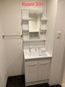 a bathroom with a white sink and a mirror at SkyHotel Kikukawa 駅徒歩2分 in Tokyo