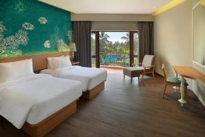 a hotel room with two beds and a balcony at Manado Tateli Resort and Convention in Manado