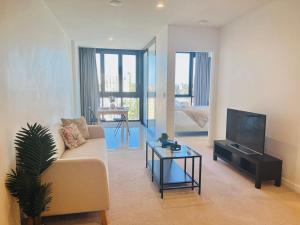 a living room with a couch and a tv at CASSA TOOWONG - Convenient 1B Apt at Central Location with Parking Managed by The Cassa in Brisbane