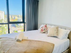 uma cama com lençóis brancos e almofadas com uma janela em CASSA TOOWONG - Convenient 1B Apt at Central Location with Parking Managed by The Cassa em Brisbane