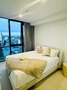 a bedroom with a large bed with a large window at CASSA TOOWONG - Convenient 1B Apt at Central Location with Parking Managed by The Cassa in Brisbane