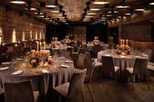 una habitación con mesas largas y sillas con velas en The London EDITION, en Londres