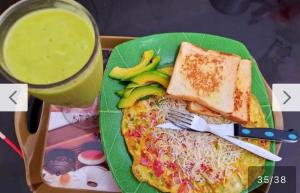 a green plate of breakfast food with toast and a drink at Nias Falaga Home in Lagudri