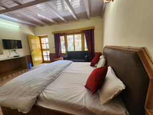 a large bed with red pillows in a room at Safarnama Homestay Manali - Himachal Kathkuni Architecture with Mountain View in Manāli