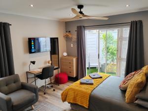 a bedroom with a bed and a chair and a television at Leafy Retreat Kenridge Trendy in Durbanville