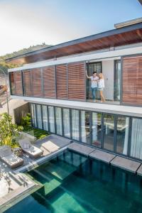 two people standing on the balcony of a house with a swimming pool at Ocean Beach Villa Nha Trang in Nha Trang