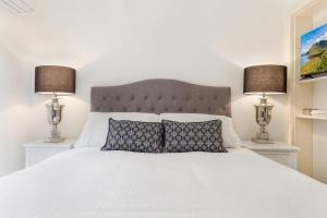 a bedroom with a white bed with two lamps at Chic CBD Studio in Heritage House with Pool & BBQ in Melbourne