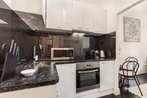 a kitchen with white cabinets and black counter tops at Chic CBD Studio in Heritage House with Pool & BBQ in Melbourne