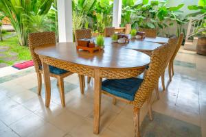 Tulus Hati Ubud Retreat في أوبود: طاولة وكراسي خشبية في غرفة بها نباتات
