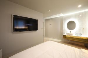 a bedroom with a flat screen tv on a wall at Changwon Denbasta Hotel Myeongseo in Changwon