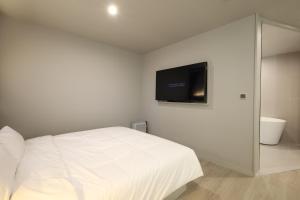 a bedroom with a white bed and a flat screen tv at Changwon Denbasta Hotel Myeongseo in Changwon