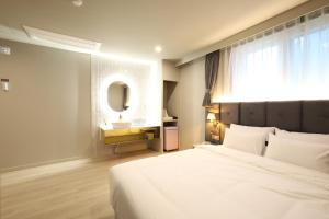 a bedroom with a bed and a sink and a mirror at 창원덴바스타호텔 명서점 in Changwon