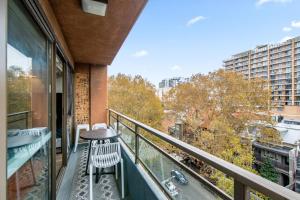 a balcony with a table and chairs on a building at Chic Studio with Pool Overlooking the City in Sydney