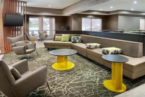 a lobby with a couch and two tables and chairs at SpringHill Suites Charlotte University Research Park in Charlotte