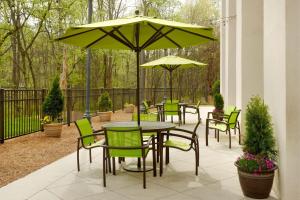 patio ze stołem, krzesłami i parasolem w obiekcie SpringHill Suites Charlotte University Research Park w mieście Charlotte