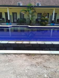 a swimming pool in front of a house at Kuta Lodge Homestay in Kuta Lombok
