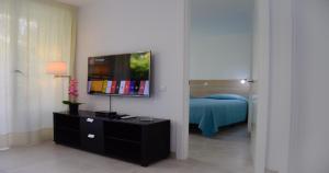 1 dormitorio con 1 cama y TV en la pared en Dunaoasis Maspalomas, en Maspalomas