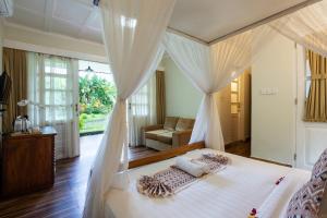 a bedroom with a white bed with a canopy at Abipraya Ubud in Ubud