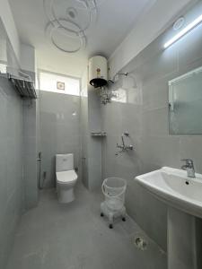 a white bathroom with a toilet and a sink at Hotel Yog Vriksh in Rishīkesh