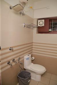 a bathroom with a toilet and a clock on the wall at raison d'être - The Residential Library in Trivandrum