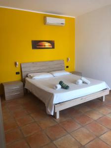 1 dormitorio con 1 cama grande y pared amarilla en Oasi, en Porto Cesareo