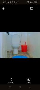 a bathroom with a white toilet and a red bucket at Greenstar home in Kisii