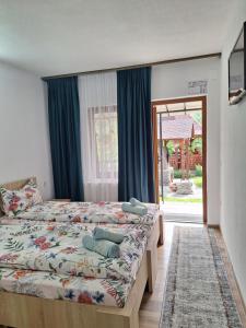 1 dormitorio con 1 cama con cortinas azules y ventana en Pensiunea Casa Ancuta en Vadu Izei